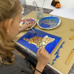 Kind malt einen Tiger mit Acrylfarbe