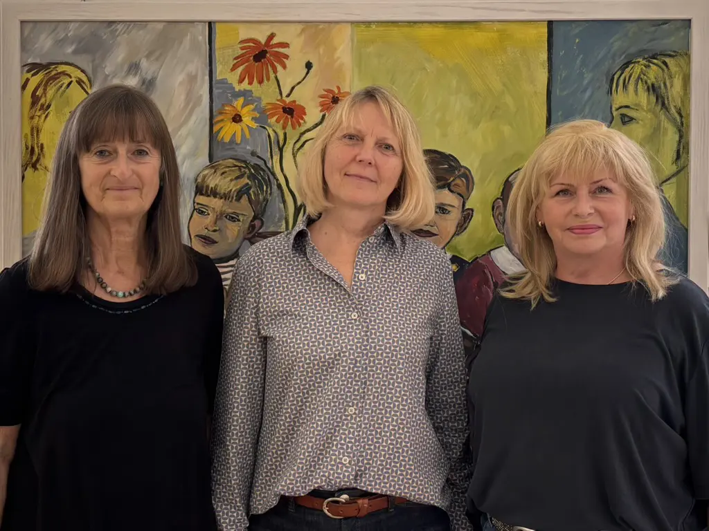 Evi Steiner-Böhm und Rsowitha Braun-Sauerstein mit der Leiterin der Regionalbibliothek Weiden Das Bild zeigt von links nach rechts Evi Steiner-Böhm, die Leiterin der Regionalbibliothek Weiden, und Rsowitha Braun-Sauerstein vor einem Bild in der Ausstellung 2026.